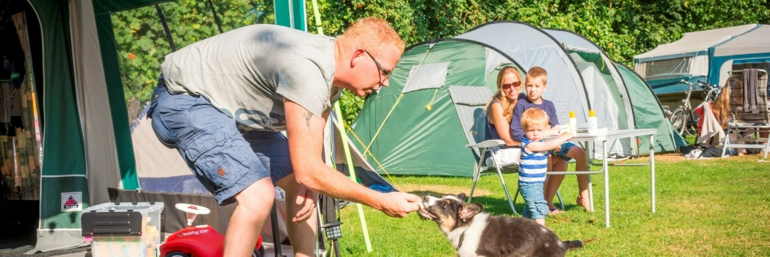 Man met hond en gezin bij tent op Vakantiepark De Krim VVV Texel