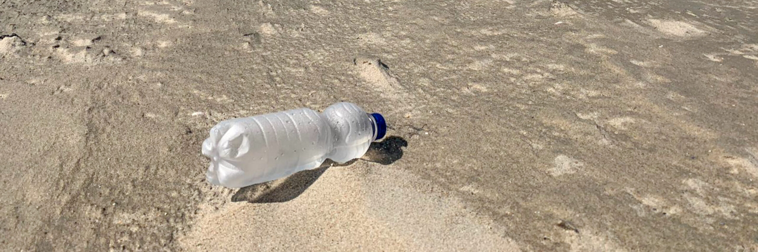 Plastic flesje op het strand