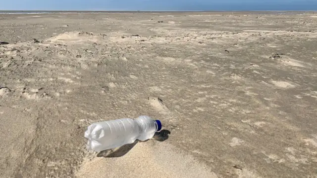 Plastic flesje op het strand