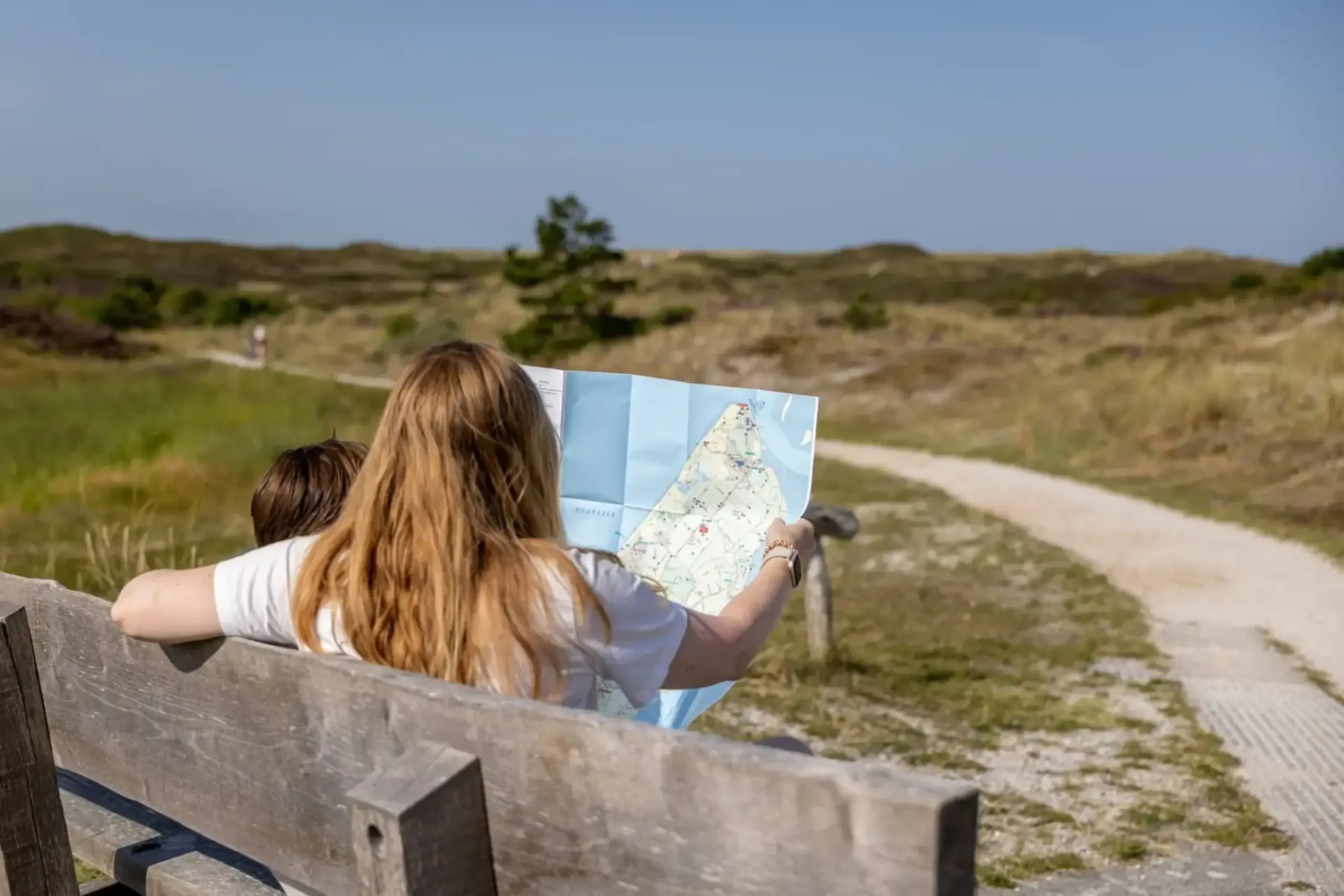 Mutter und Kind betrachten Karte in den Dünen